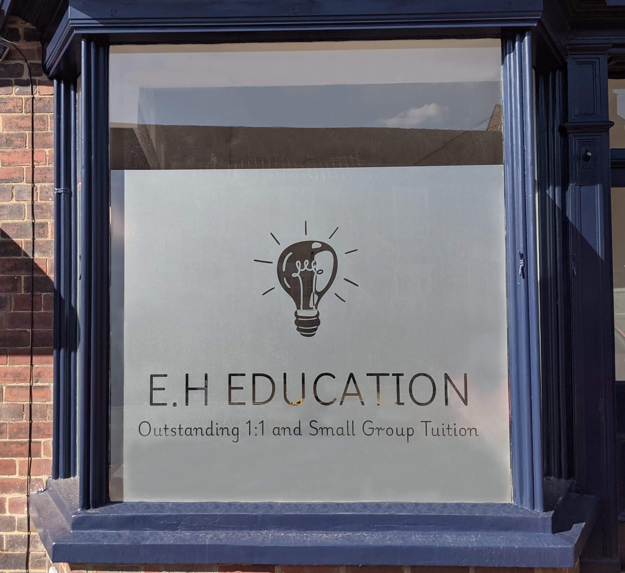A frosted window with a blue sill. The window has a light bulb and is titled "E.H Education."