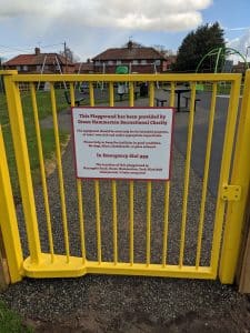 A yellow gate with a white sign with red letters.