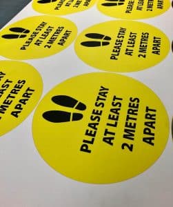 Six floor labels instructing readers to stay 2 metres apart.