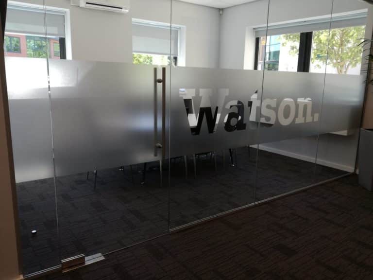 Etched window graphics on a glass wall, beyond which is a conference room. The graphics say "Watson."