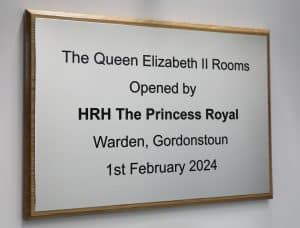 A white aluminium sign titled "Queen Elizabeth II Rooms."