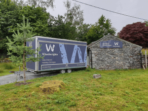 A stone building and a trailer, both displaying the same blue signage.