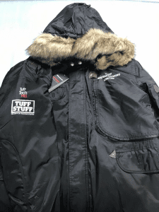 A black coat with a fur-lined hood and a Tuff Stuff logo on the right shoulder.