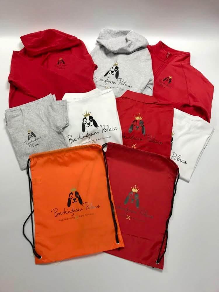 An array of red, white, gray and orange T-shirts, hoodies, jackets, and drawstring bags, all with the Barkingham Palace logo.