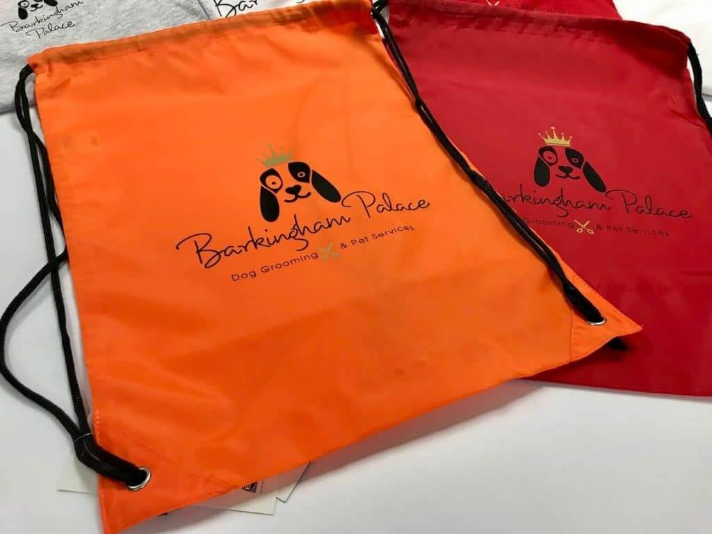 Two drawstring bags, one orange and one red, with the Barkingham Palace logo.