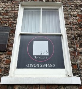 A window displaying a GSB Solicitors graphic, seen from the front.
