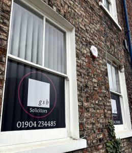 A window displaying a GSB Solicitors graphic, seen from an angle.