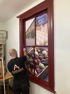 A man installing the window-shaped sign.