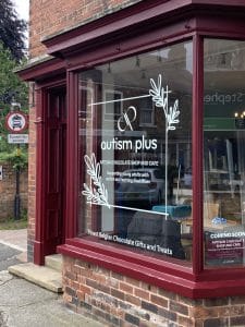 An exterior window with a decal that says "autism plus".