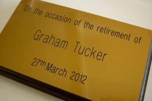 A yellow plastic plaque comemmorating the retirement of Graham Tucker.