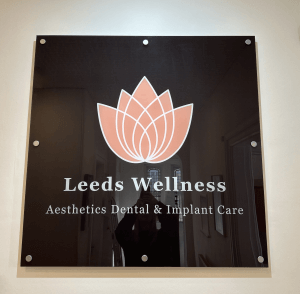 A black Perspex sign saying Leeds Wellness Aesthetics Dental & Implant Care.