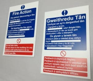 Two fire action signs, one in English, one in Welsh.